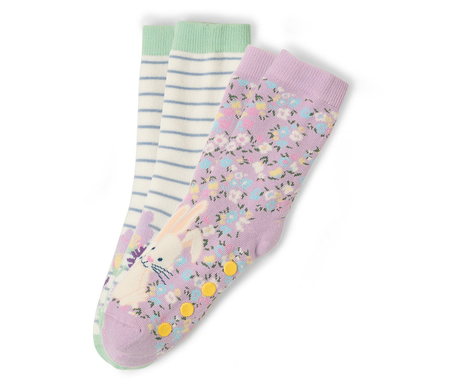 Trois paires de chaussettes sont posées sur un fond blanc. Une paire est violette avec un motif floral et un imprimé de lapin. Une paire est blanche avec des rayures bleues et une bordure verte.