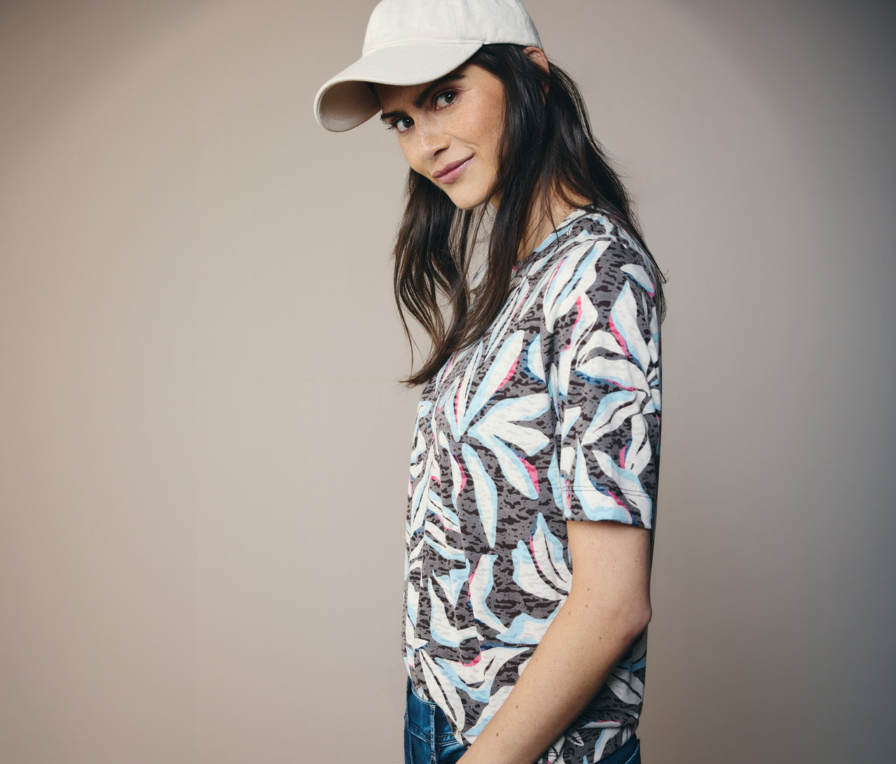 Femme portant une casquette beige et un t-shirt à manches courtes bleu avec imprimé feuilles CECIL.