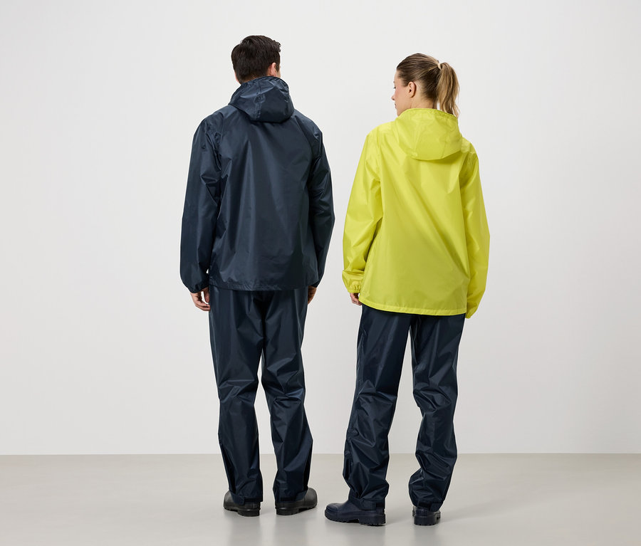 Vue arrière de deux personnes, l'une portant une veste de pluie et un pantalon de pluie bleu marine, l'autre portant une veste de pluie jaune et un pantalon de pluie bleu marine.