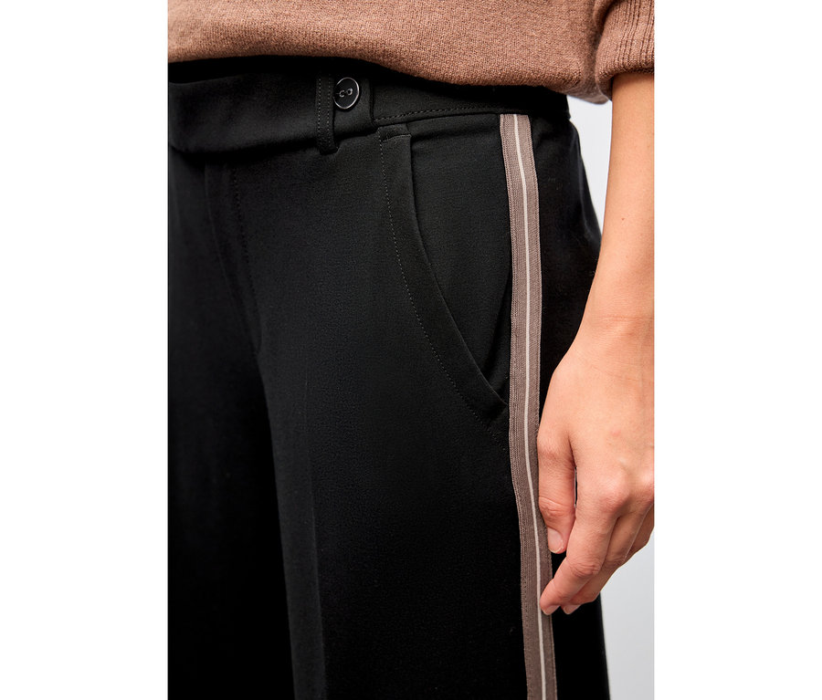 Gros plan d'une personne portant un pantalon noir Straight Leg avec galon de Street One.