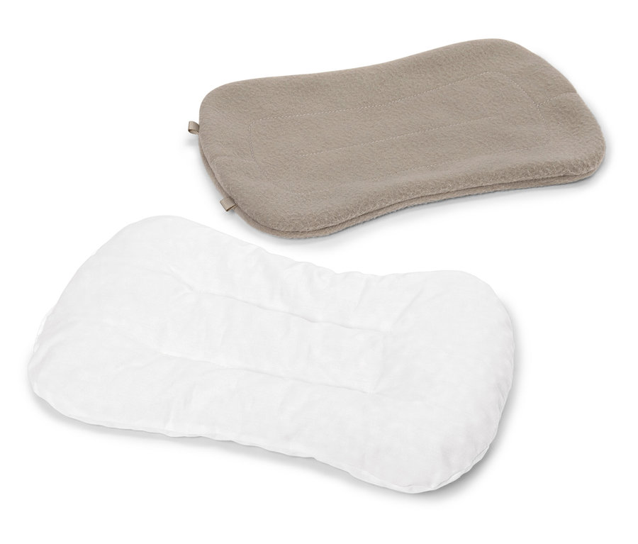 Un oreiller blanc matelassé est posé sous un oreiller beige sur un fond blanc.