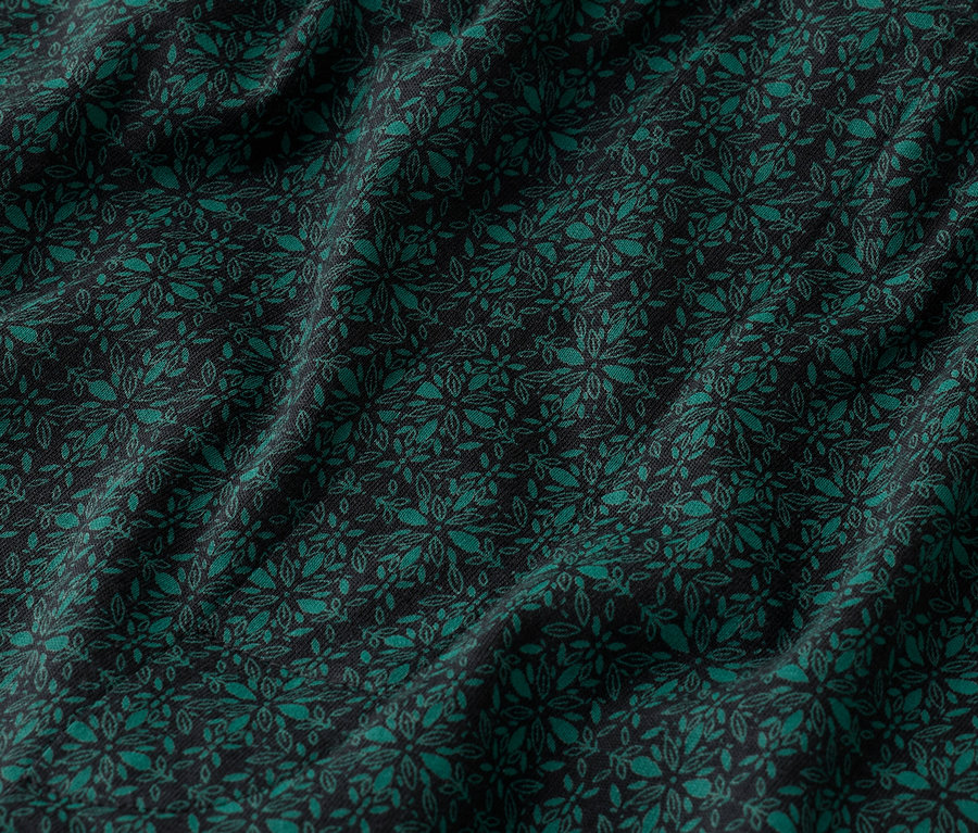Gros plan d'un tissu bleu foncé avec un motif floral vert émeraude.