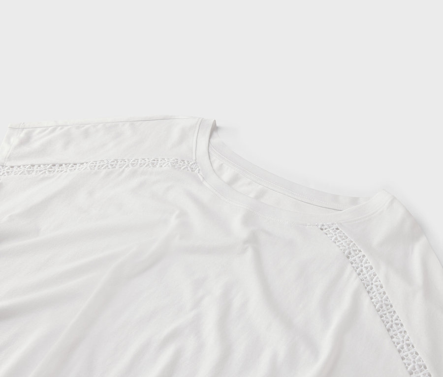 Gros plan d'un t-shirt blanc avec des finitions en dentelle au niveau du col et de l'épaule.