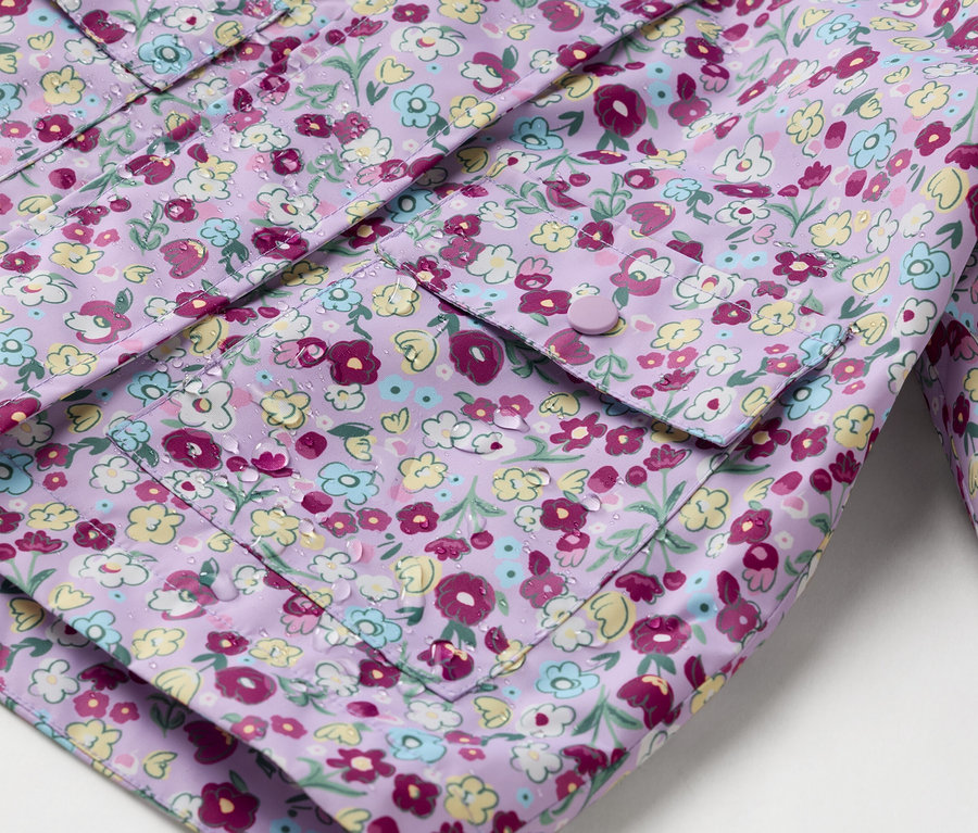 Gros plan d'un imperméable violet à fleurs avec des poches plaquées boutonnées.