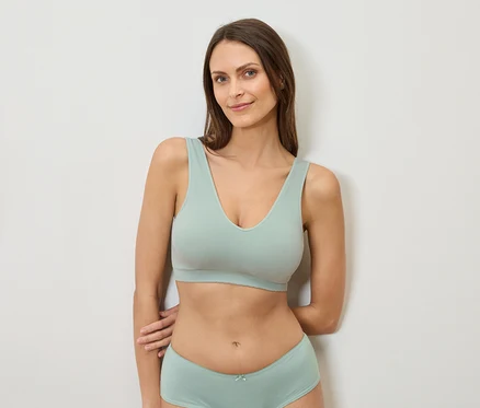 Femme appuyée contre un mur portant un soutien-gorge et des sous-vêtements vert menthe.