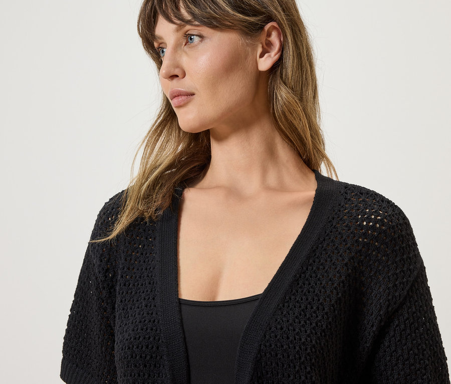 Femme portant un cardigan noir crocheté.