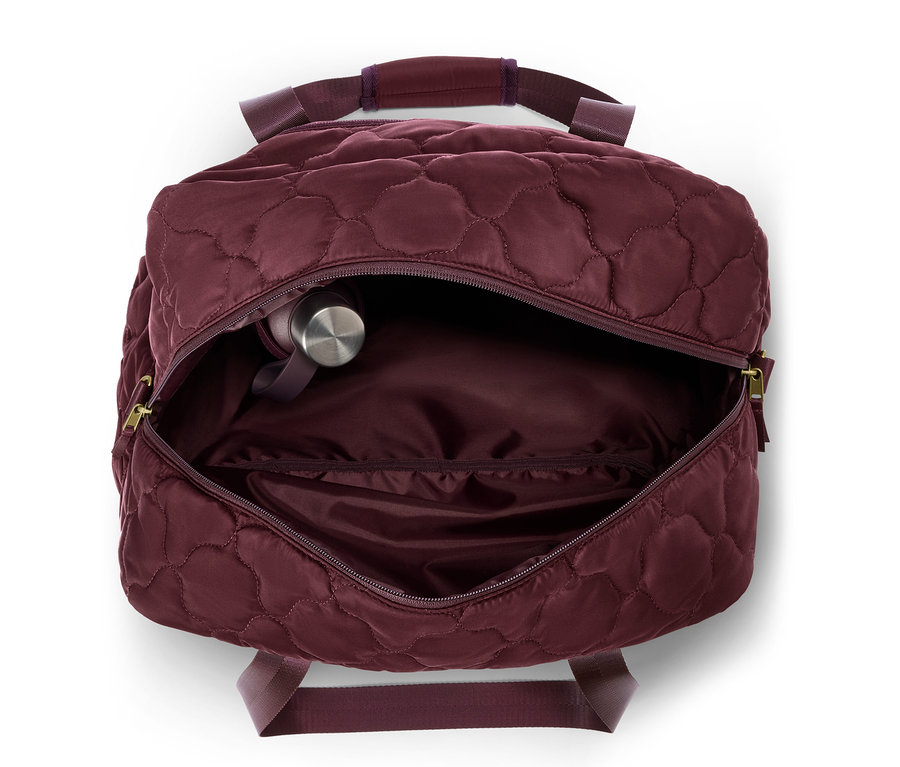 Sac ouvert bordeaux matelassé avec une bouteille d'eau argentée à l'intérieur.