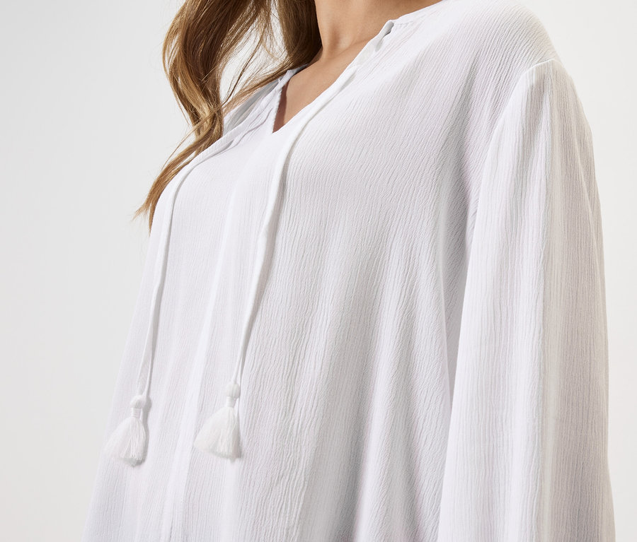 Gros plan d'une femme portant un chemisier blanc à cordon.