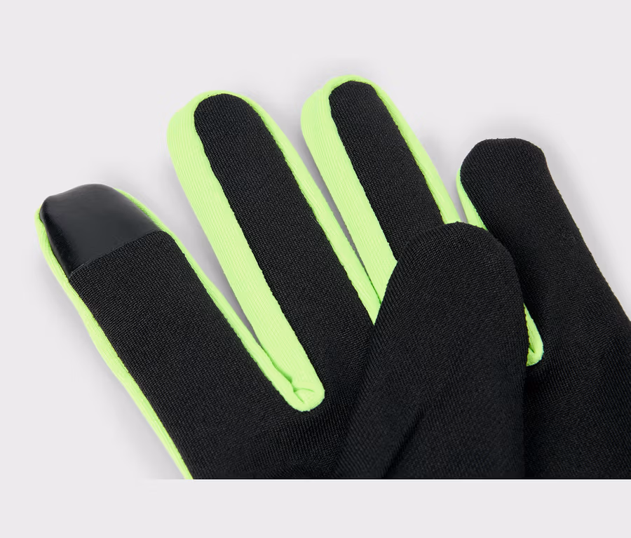 Gros plan d'un gant noir avec des bordures vert fluo le long des doigts. Le bout de l'index présente un patch noir et lisse.