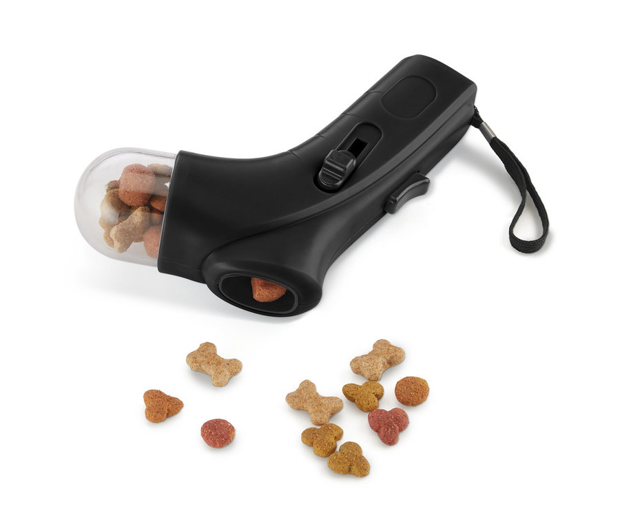 Lanceur d'aliments pour animaux noir avec un récipient plein et des aliments éparpillés en dessous.