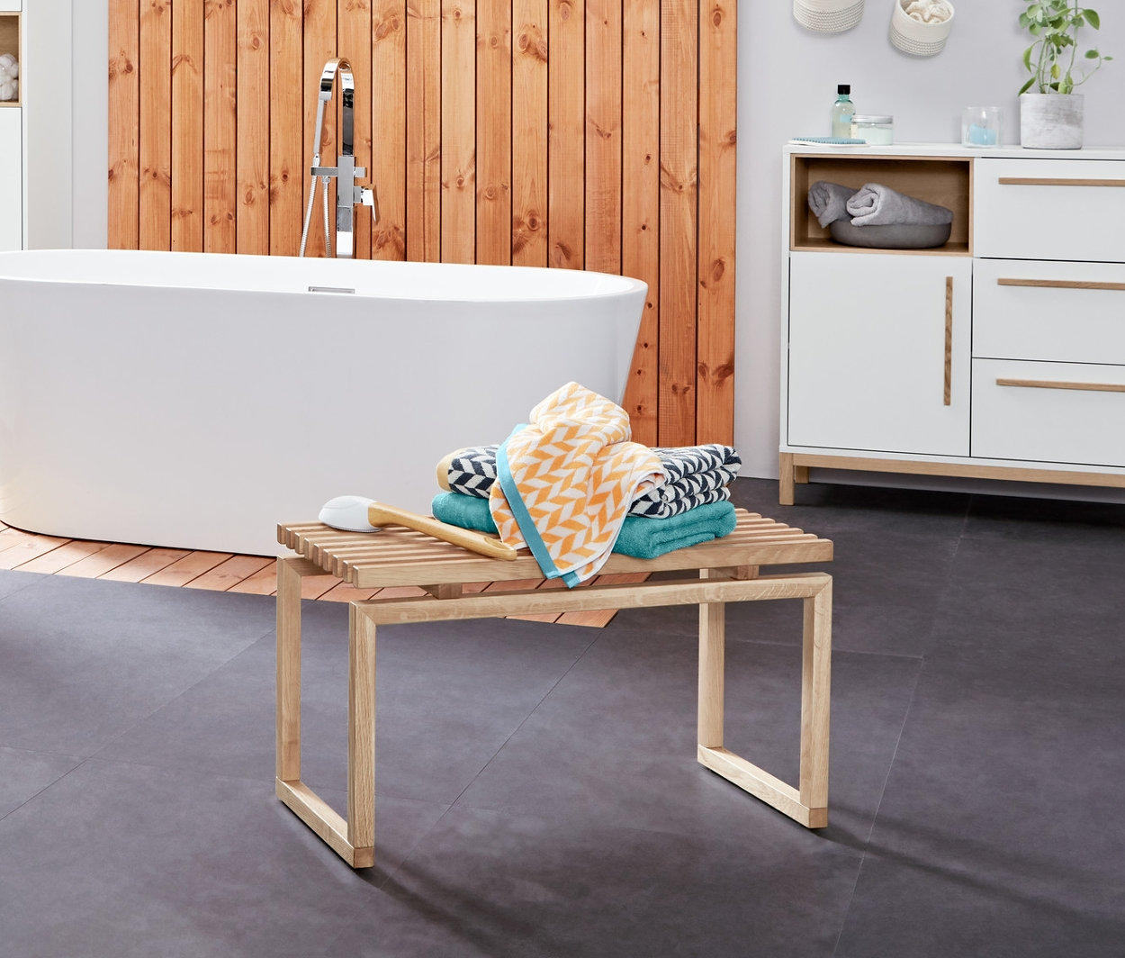 Intérieur de salle de bain avec un chariot d’appoint pour salle de bains «Eklund», buffet de salle de bains «Eklund», armoire haute pour salle de bains «Eklund» et linge de bain en jacquard.