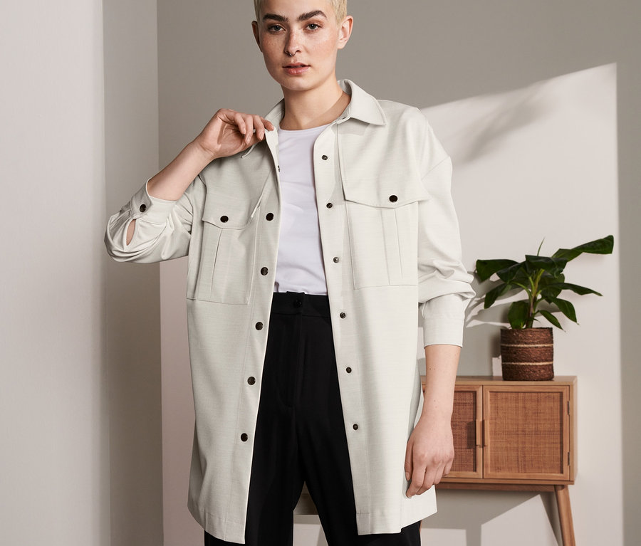 Une femme portant une surchemise, un t-shirt blanc et un pantalon noir.