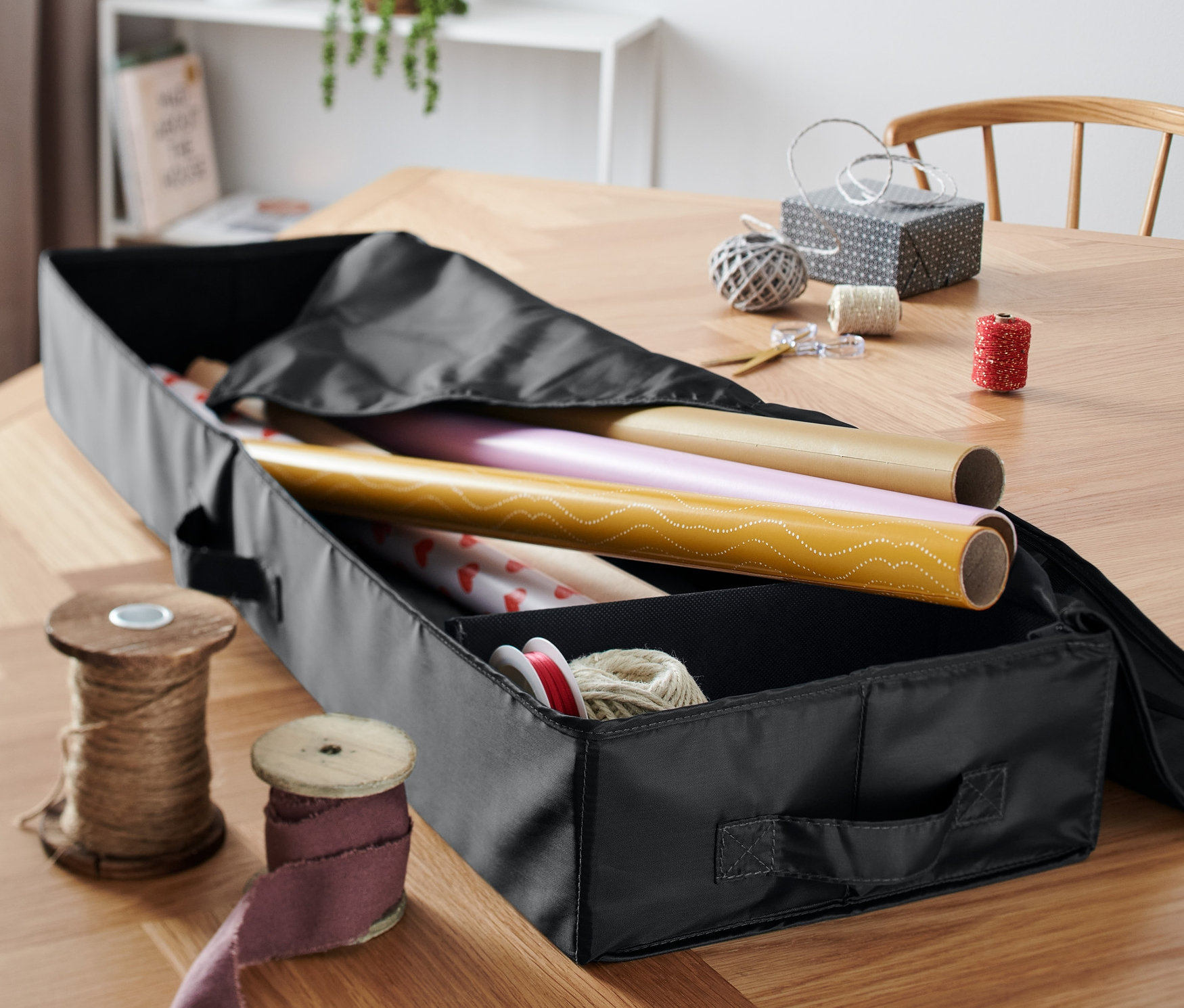 Un organisateur noir pour papier cadeau avec du papier cadeau à l'intérieur.