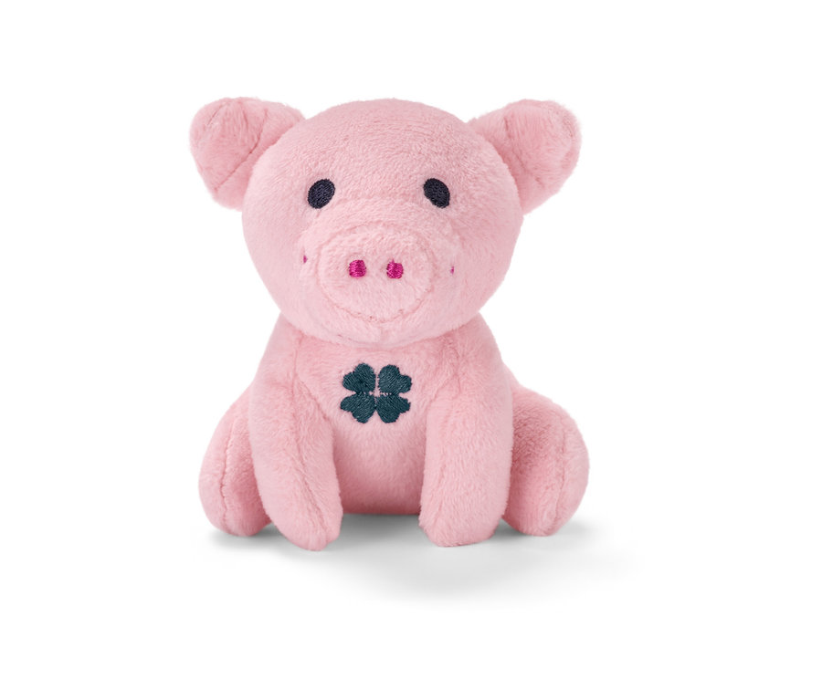 Cochon porte-bonheur sonore en peluche rose assis avec un trèfle noir sur le ventre.