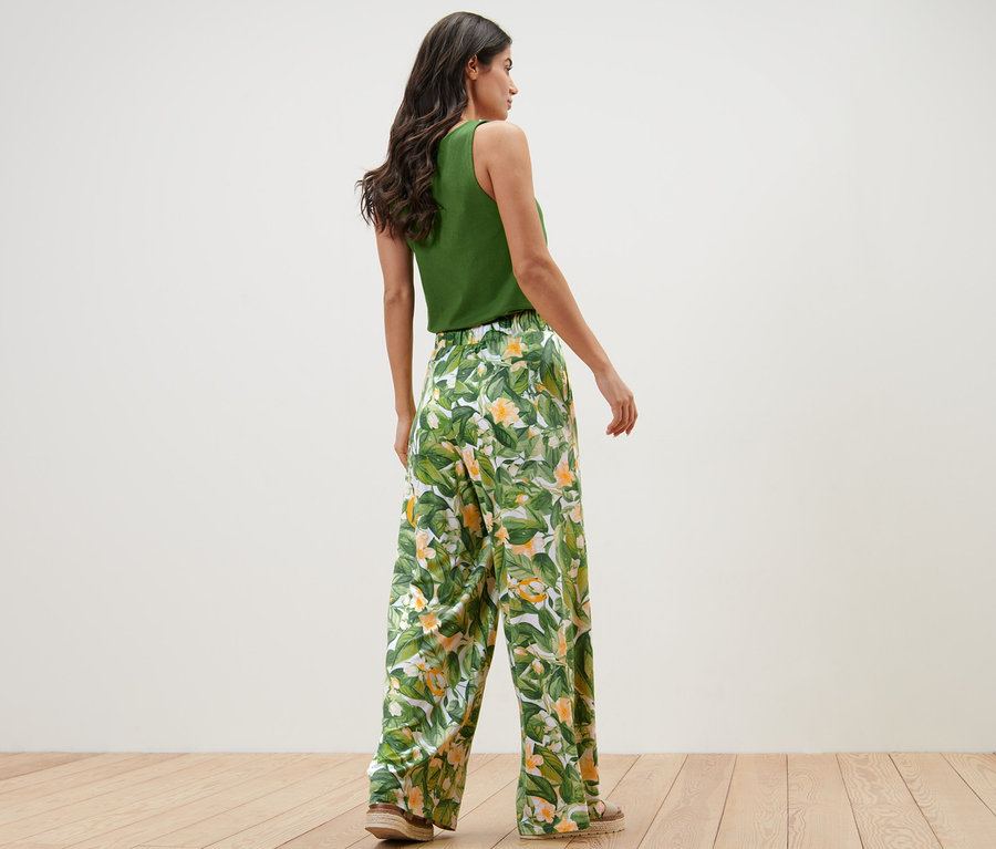 Femme posant dans un haut vert et un pantalon palazzo imprimé.
