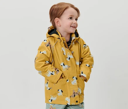 Un garçon porte une veste de pluie thermique pour enfant à motif dalmatien et un pantalon imprimé.