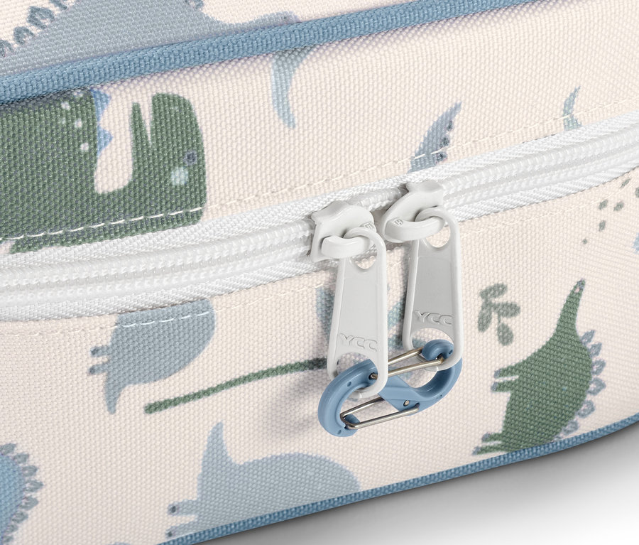 Détail d'une trousse à pharmacie à motif de dinosaures avec fermeture éclair blanche.