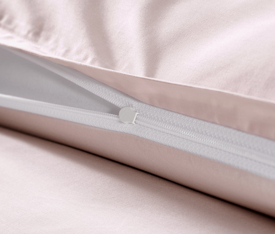 Gros plan d'une parure de lit rose en satin de coton avec fermeture éclair.