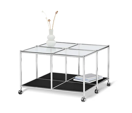 Table basse à roulettes « CN3 » noire avec plateau en verre, étagère noire et vase avec des plantes.