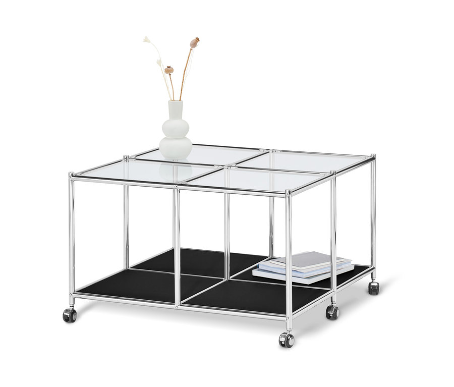 Table basse à roulettes « CN3 » noire avec plateau en verre, étagère noire et vase avec des plantes.
