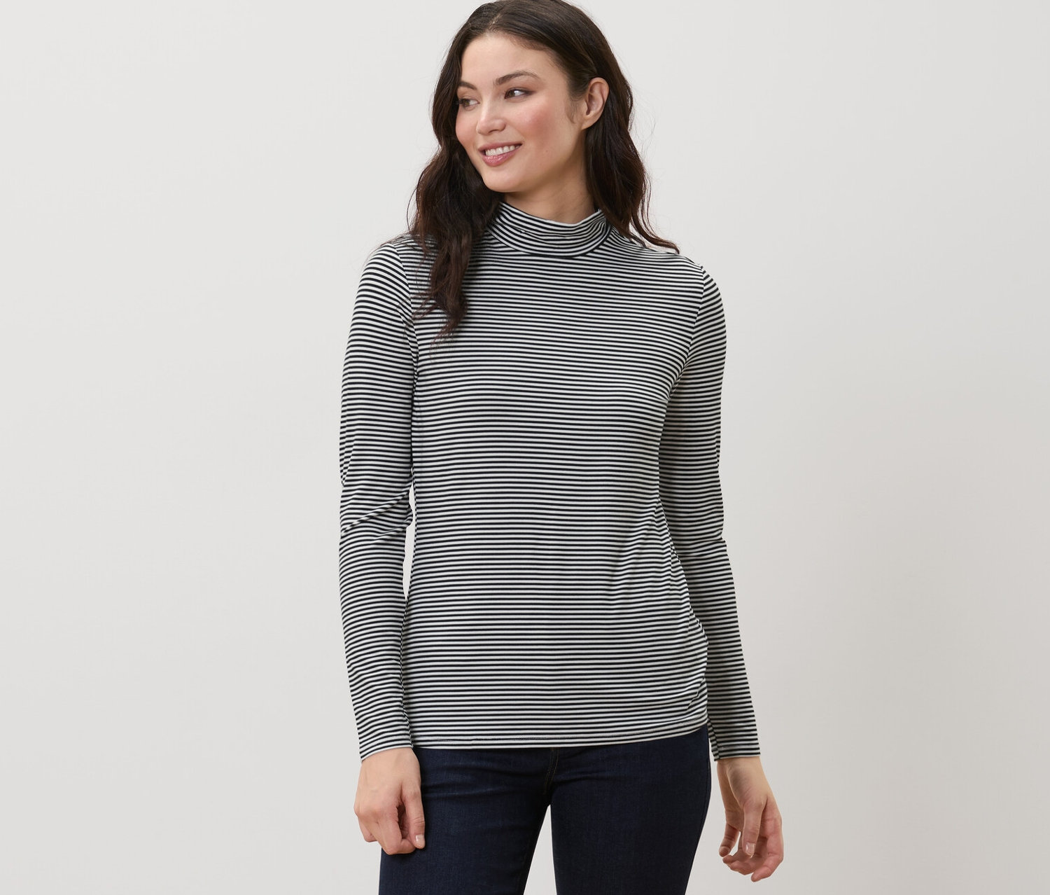 Une femme porte une blouse rayée à col montant et un pantalon bleu marine.