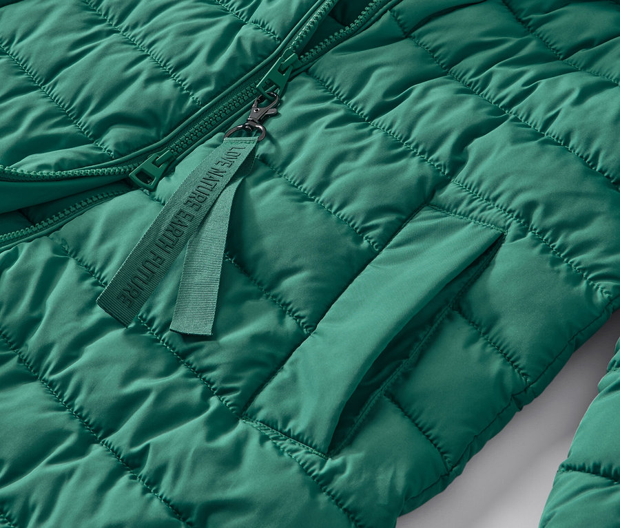 Détail d'un manteau matelassé à capuche vert.