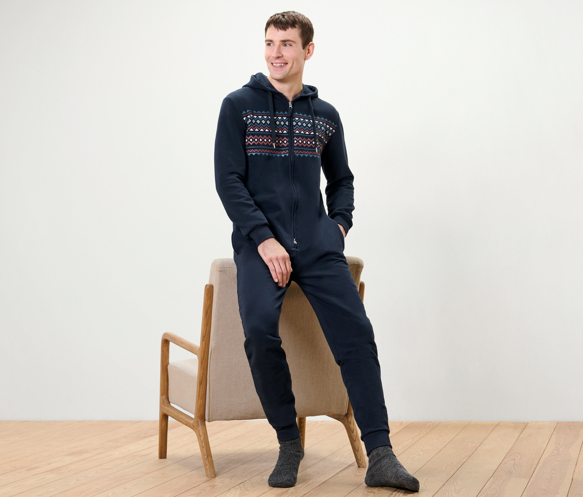 Homme assis sur une chaise, portant une combinaison d’intérieur bleue.