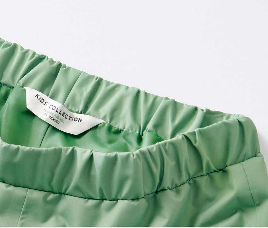 Détail d'un pantalon de pluie pour enfant, vert gazon.