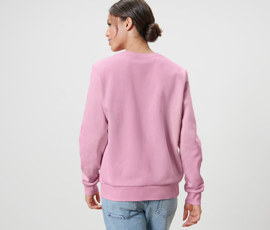 Une femme vue de dos porte un sweatshirt rose pâle et un jean.