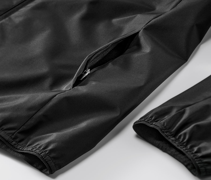 Détail d'une veste de sport coupe-vent noire avec une poche zippée.