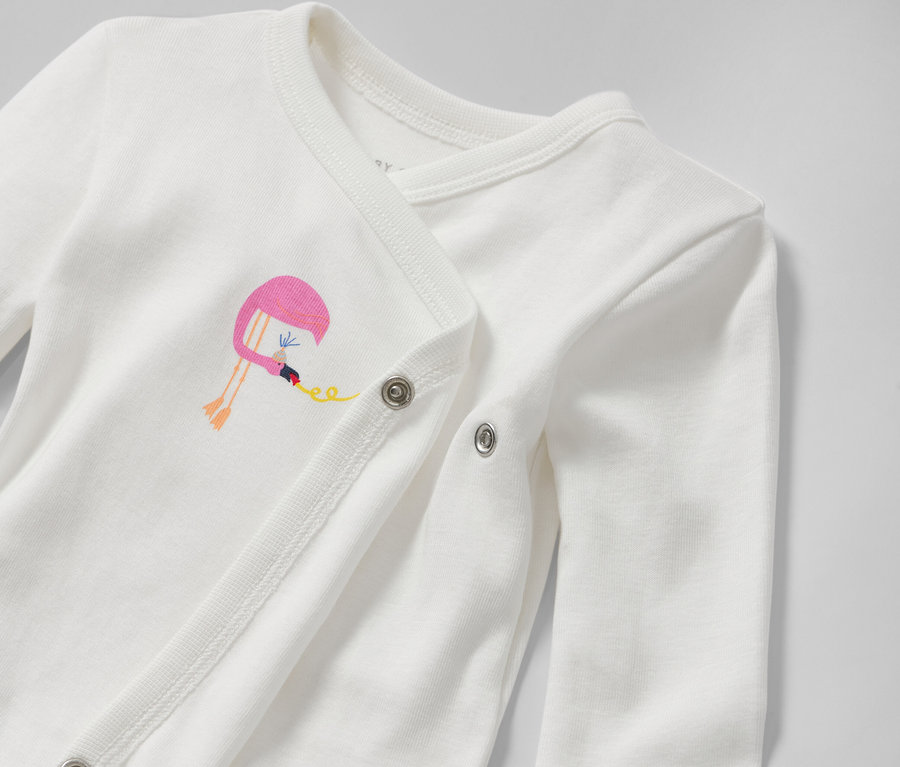 Gros plan sur un body blanc évolutif pour bébé avec une broderie flamant rose.