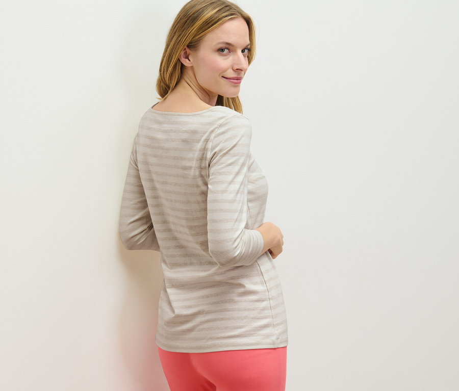 Femme regardant par-dessus son épaule portant un t-shirt rayé à manches 3/4.
