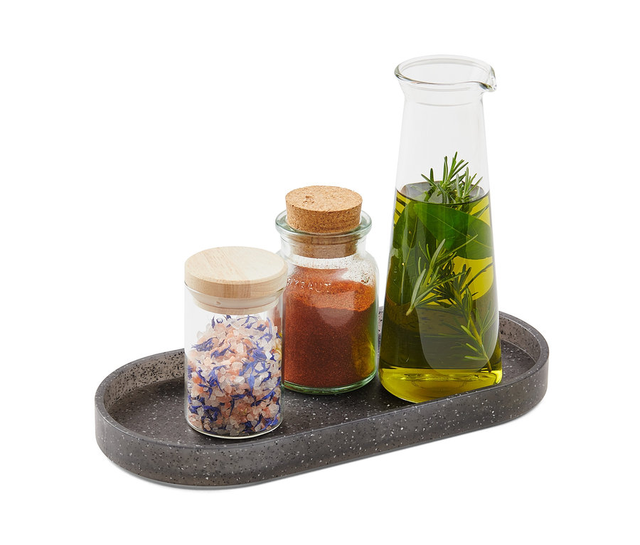 Trois bocaux d'épices et d'huile reposent sur un comptoir de cuisine aspect granit.
