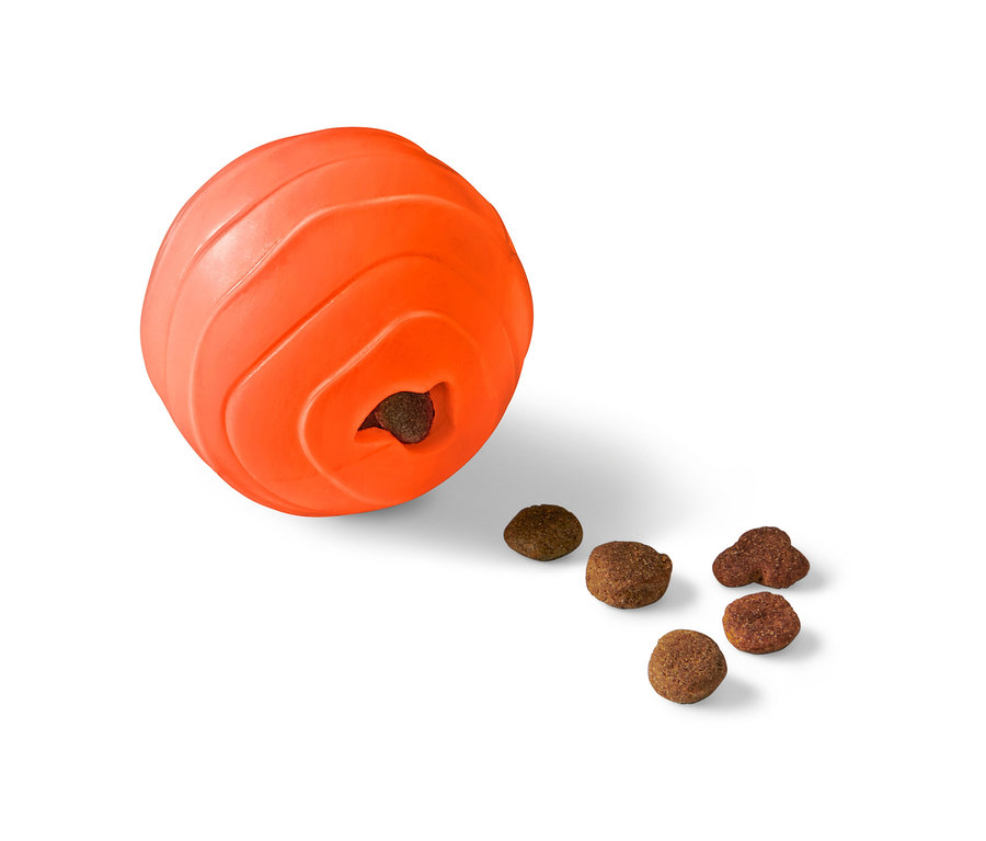 Balle à friandises orange pour chien avec une ouverture d'où tombent des croquettes.