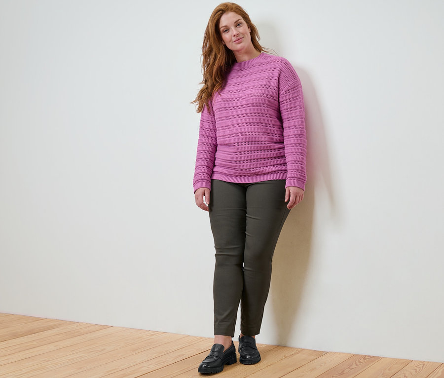Femme posant en pull à motif ajouré et pantalon stretch.