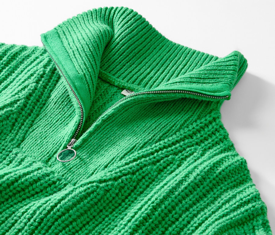 Vue détaillée d'un pull camionneur en grosse maille vert avec fermeture éclair ouverte.