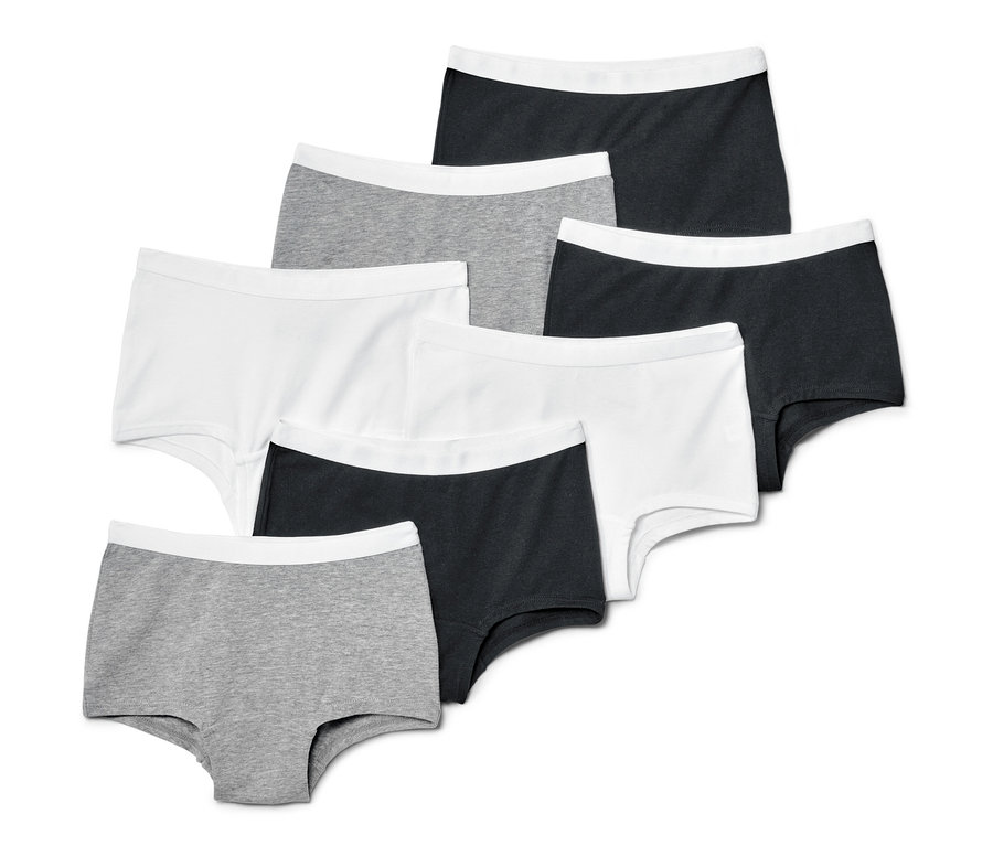 Sept culottes pour enfant, grises, blanches et noires, disposées dans une composition soignée.