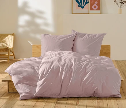 Parure de lit en percale rose de taille standard et grande taille sur un lit.