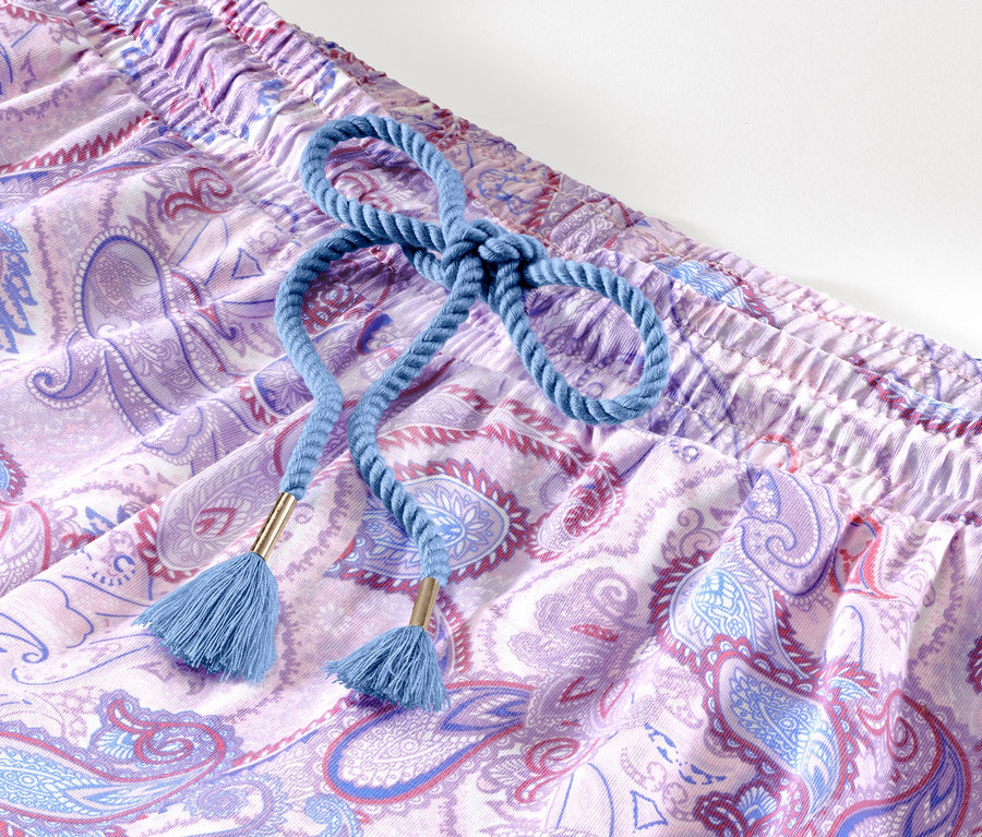 Gros plan sur un ensemble pyjama shorty avec un motif cachemire violet et un cordon bleu.