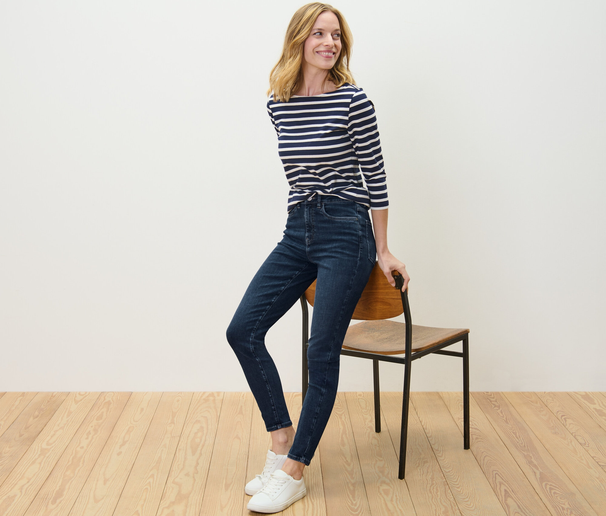 Une femme pose, appuyée contre une chaise, et porte un jean skinny – Fit « Hanna ».