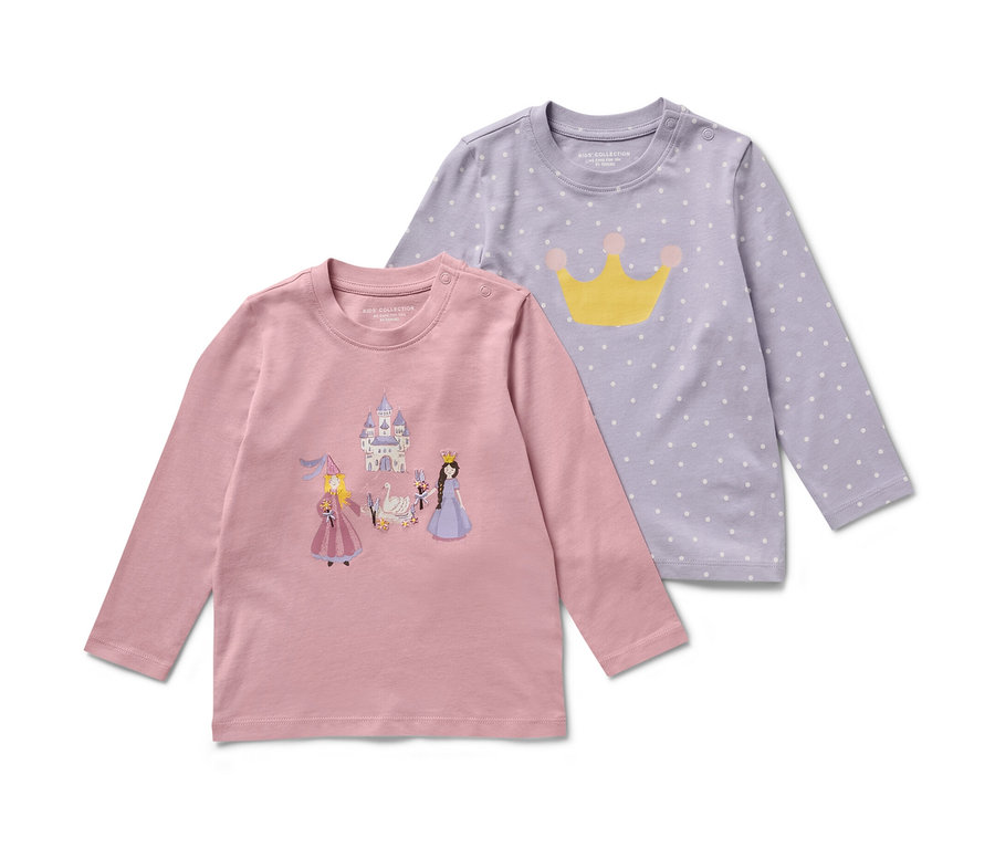Deux t-shirts à manches longues pour enfants avec motif princesse. L'un est rose avec des images de château et de princesses, l'autre violet avec des pois blancs et une couronne jaune.
