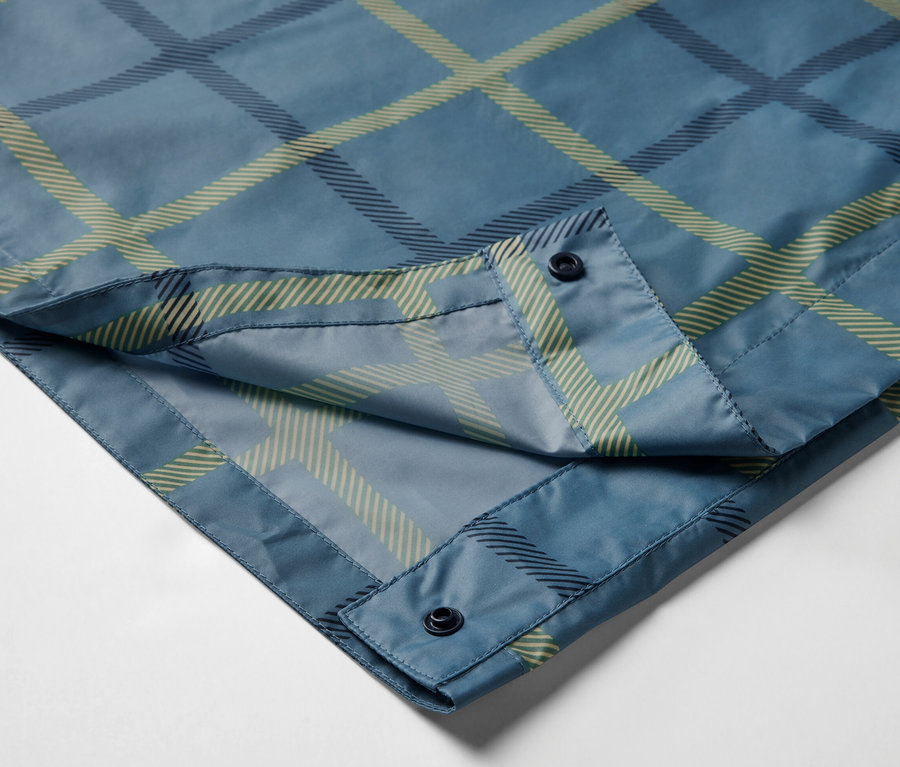 Gros plan sur un poncho de pluie à carreaux bleus avec des manches et des boutons.
