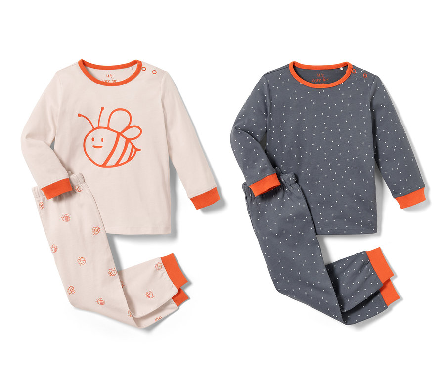 Deux pyjamas pour tout-petits, un rose avec un motif d'abeille et un bleu avec des pois blancs.