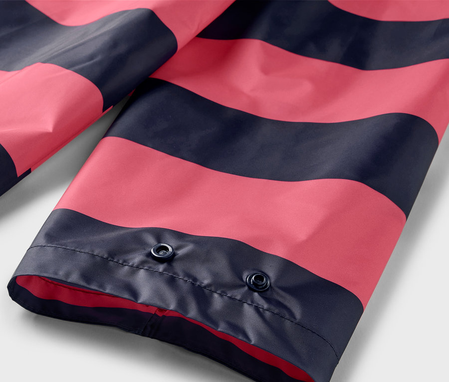 Gros plan sur un poncho de pluie à rayures roses et bleu marine avec des boutons-pression.