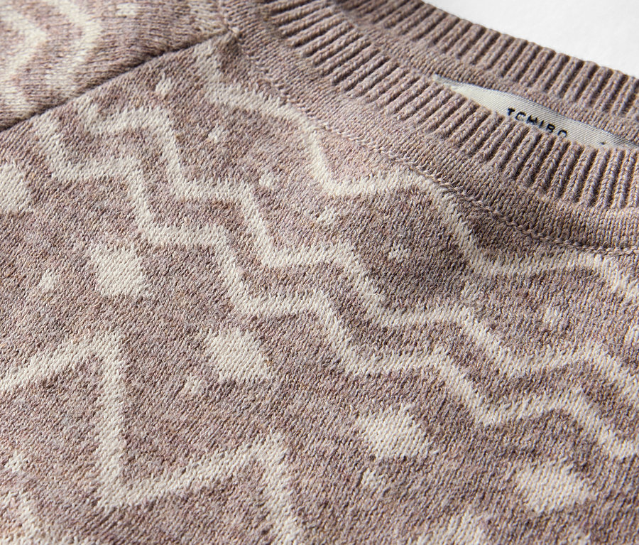 Gros plan d'un pull marron à motifs.