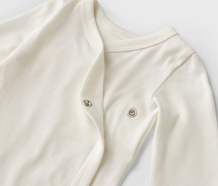 Gros plan sur un body blanc à manches longues pour bébé, faisant partie d'un ensemble de 5 bodies évolutifs.