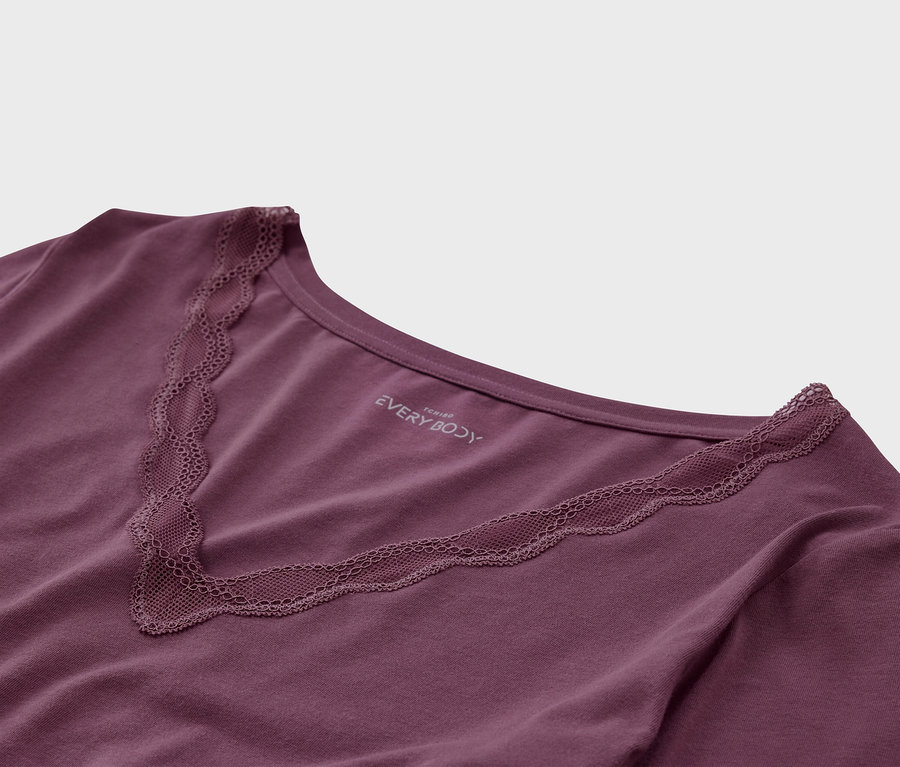 Gros plan d'un t-shirt violet avec bordure en dentelle sur l'encolure en V.