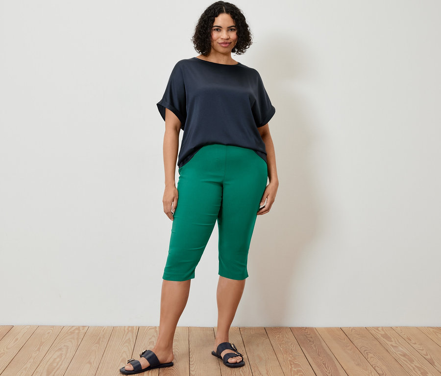 Une femme debout porte un pantalon 3/4 en bengaline et une blouse bimatière bleu marine.