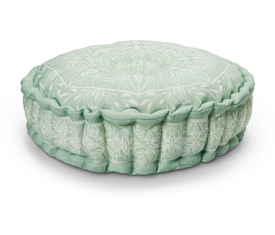 Un coussin de sol vert avec un motif floral blanc.