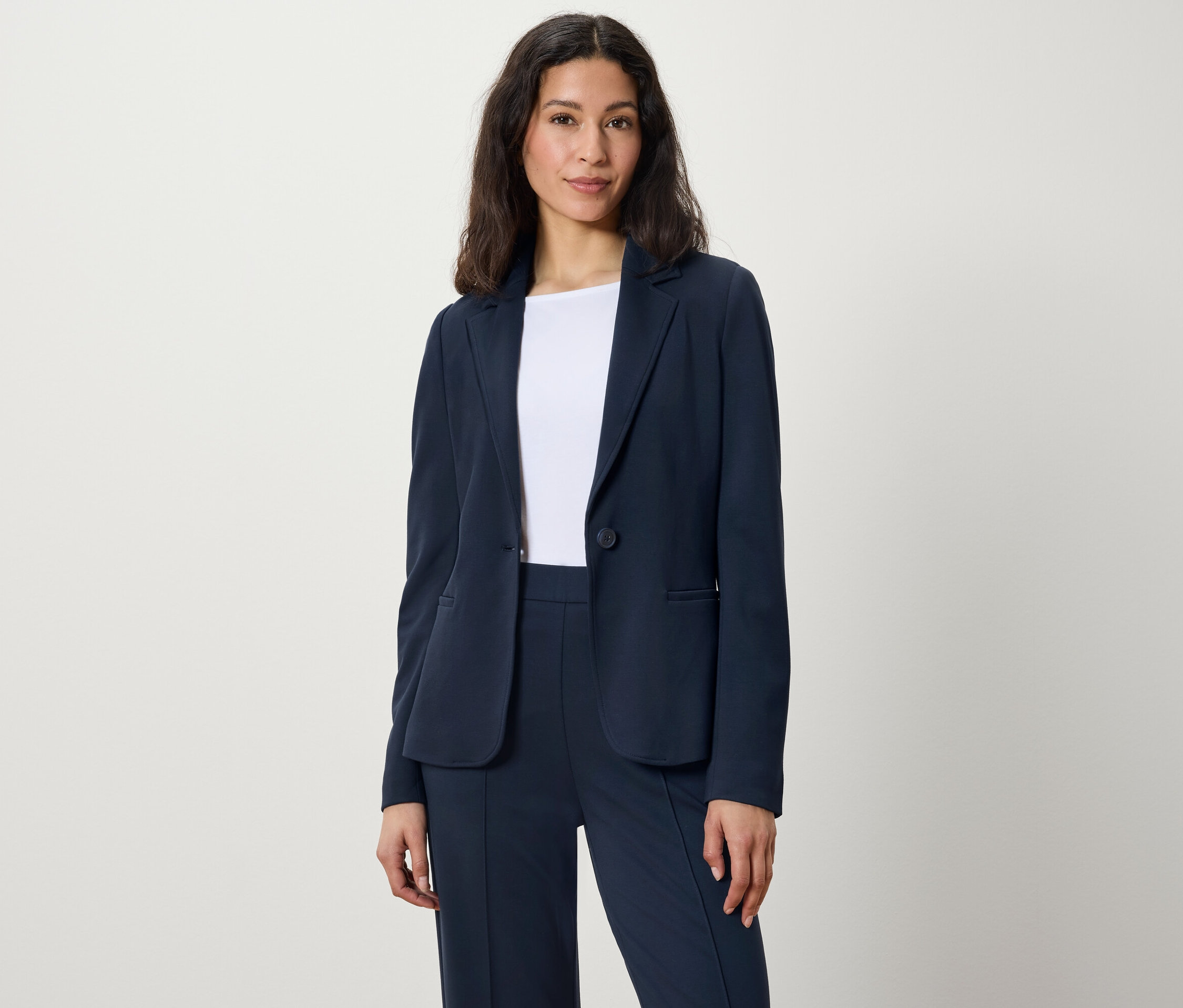 Femme posant en blazer et pantalon bleu marine.